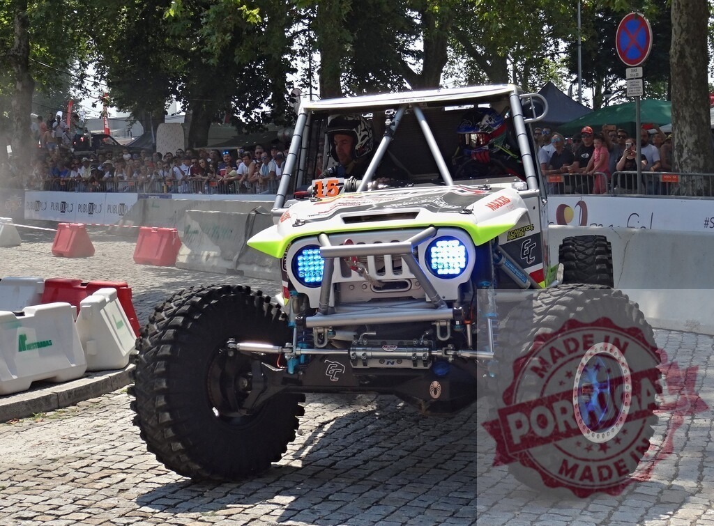 Powerful 4x4 jeep competing in an urban off-road competition with led headlights turned on | Modified Jeep with large tires and led headlights participates in an urban off-road race, driving over cobblestones in front of spectators - Realisiert mit Pictrs.com