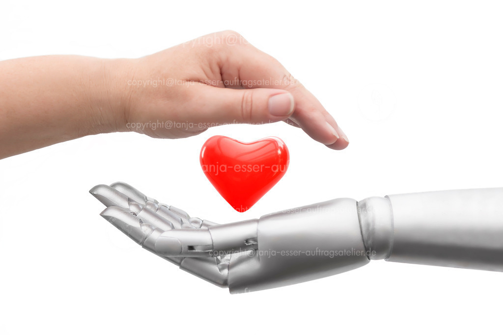 A human hand and a robot hand protect a heart | Conceptual photo of how life is protected. A robot hand and a human hand protectively surround a heart. Isolated in front of white background.