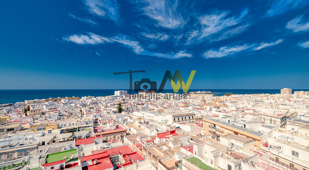 Panoramaansicht von Cadiz,weiße Häuser bis zum Meer | Das Bild zeigt eine Panoramaansicht der Altstadt von Cádiz, Spanien. Cádiz gilt als die älteste durchgehend bewohnte Stadt Europas. Der Torre Tavira war im 18. Jahrhundert der offizielle Wachturm des Hafens von Cádiz und ist der höchste Punkt der Stadt. Der Turm beherbergt eine berühmte Camera Obscura, die erste in Spanien, die Live-Bilder der Umgebung auf eine Leinwand projiziert. Die Stadt ist bekannt für ihre historischen Gebäude wie die Kathedrale und ihren einzigartigen Aufbau, der von einer jahrtausendelangen Geschichte zeugt.  - Realisiert mit Pictrs.com