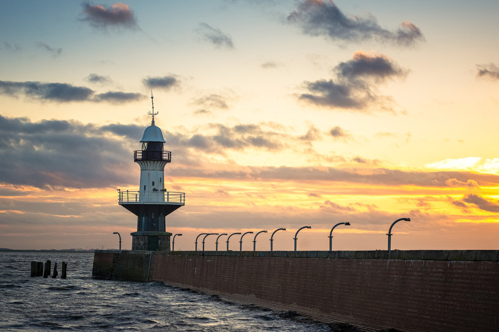 Leuchtturm "Mole 1" Brunsbüttel | Der historische Leuchtturm "Mole 1" in Brunsbüttel präsentiert sich majestätisch vor dem beeindruckenden Hintergrund eines malerischen Sonnenuntergangs. In diesem idyllischen Szenario wird der Leuchtturm "Mole 1" zu einem zeitlosen Symbol der Schifffahrtsgeschichte, das in der malerischen Kulisse eines Sonnenuntergangs seinen ganz eigenen Charme entfaltet.