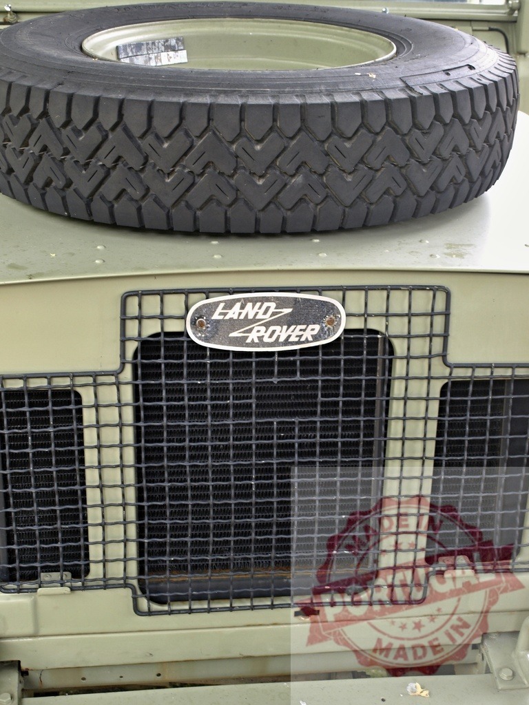Land Rover vintage 4x4 off-road vehicle detail | Land Rover vintage 4x4 off-road vehicle showing grille, emblem, and spare tire - Realized with Pictrs.com
