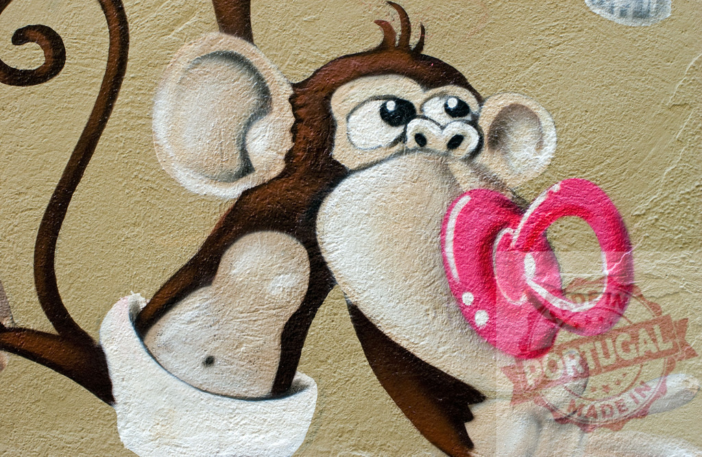 Cartoon monkey graffiti holding two pink heart rings | Detailed close-up of a playful cartoon monkey holding pink heart rings on a textured wall - Realisiert mit Pictrs.com