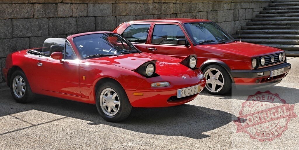 Red Mazda MX-5 Miata and Volkswagen Golf Mk2 cars parked | Two red classic cars, a Mazda MX-5 Miata roadster and Volkswagen Golf Mk2, parked together - Realisiert mit Pictrs.com