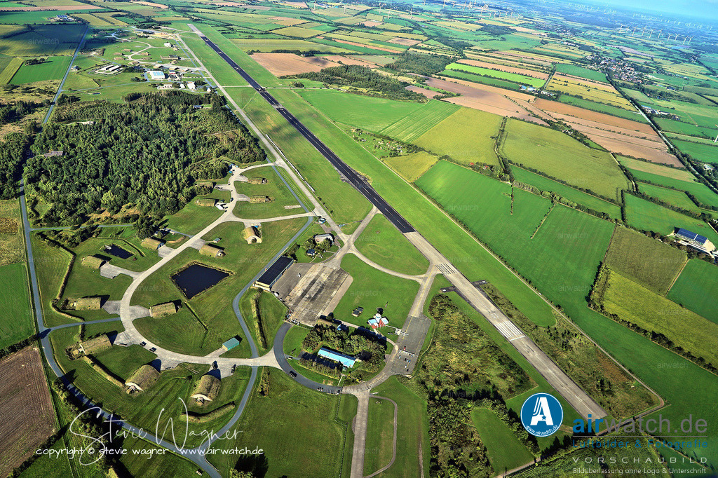 Luftbild Flughafen Husum-Schwesing - Die 1.450 Meter lange Asphaltbahn (Piste 03/21) ermöglicht einen sicheren Flugbetrieb | Die 1.450 Meter lange Asphaltbahn - Piste 03 / 21 - ermöglicht einen sicheren Flugbetrieb unter nordseitigen Wetterbedingungen. Der Flughafen fungiert als Basis für Offshore-Versorgungsflüge zu Windparks und der Forschungsplattform FINO 3 auf der Nordsee. Zudem werden Rundflüge über das Wattenmeer, die nordfriesischen Inseln und die Halligen angeboten.  - Bundeswehr Geschichte - LeKG 41: Das zentrale Kampfflugzeug des LeKG 41 war von 1966 bis 1980 die Fiat G.91, insbesondere die Versionen G.91 R/3 und T/3. Die Umrüstung begann 1963, nachdem das Geschwader noch mit der F-84F Thunderstreak ausgestattet war. - Geschichte JaboG 41: Das Jagdbombergeschwader 41 (JaboG 41) war ein fliegender Verband der Luftwaffe, der von 1980 bis 1993 am Standort Husum stationiert war. Es ging aus dem Leichten Kampfgeschwader 41 hervor und wurde mit der Einführung des Alpha Jet im Jahr 1980 in JaboG 41 umbenannt.