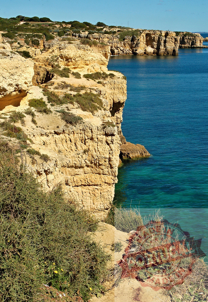 Algarve coastline with golden cliffs facing Atlantic ocean | Golden cliffs and clear blue water forming the rugged Atlantic coastline in southern Portugal - Realized with Pictrs.com
