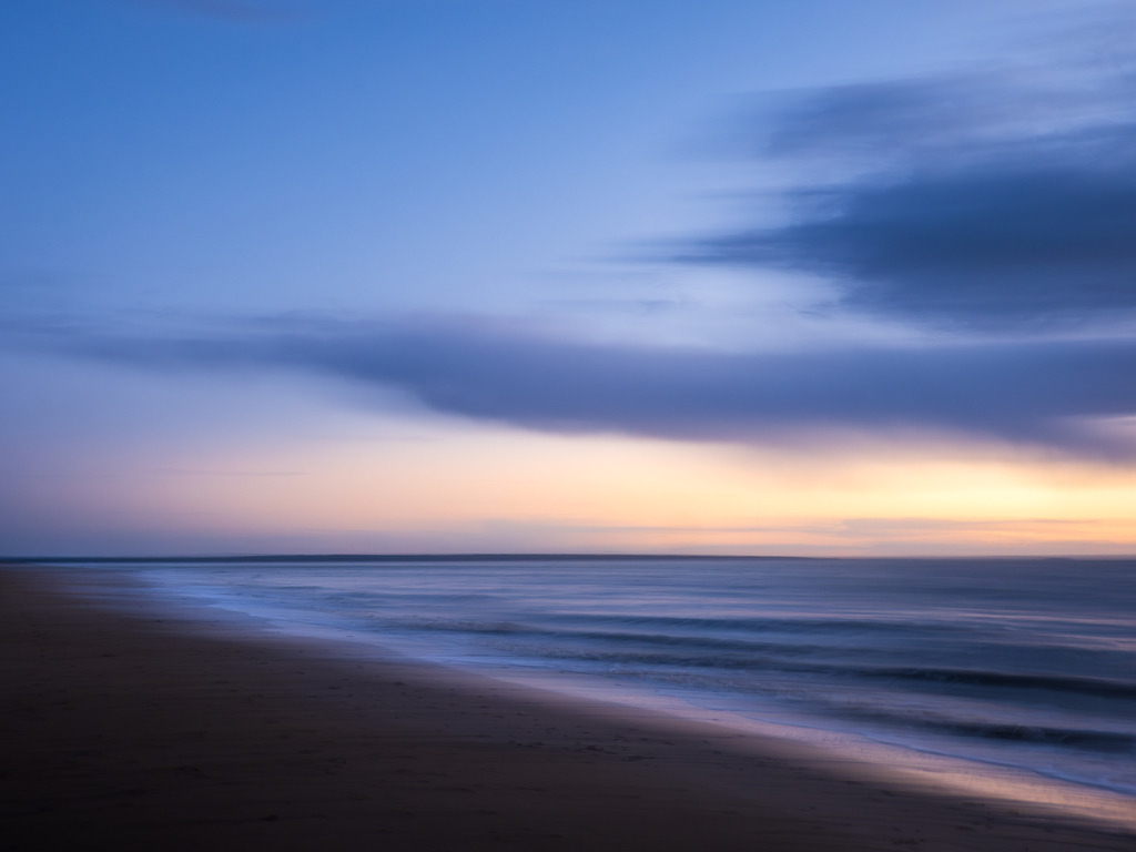Ruf der Stille | Der Blick gleitet über den weichen Sand der Bucht von Mont-Saint-Michel, der in zarten Pastelltönen von warmem Beige in sanfte Rosé- und Blaunuancen übergeht – als würde der Strand selbst in den Himmel atmen. Die Konturen der Landschaft sind reduziert auf ein stilles Fließen.Verträumte Wolkenformationen treiben gemächlich über das Bild, lösen sich auf wie Gedanken, die kommen und gehen dürfen. Alles wirkt entrückt und doch greifbar, wie ein stiller Traum, der beim Erwachen noch lange nachhallt.Dieses Bild ist eine Einladung zum Verweilen, in sich hineinfühlen und um dem Ruf der Seele zu lauschen – dort, wo Farben zu Empfindungen werden, wo Stille zu deiner Seele spricht und das Flüchtige für einen Augenblick Bestand hat. - Powered by Pictrs.com