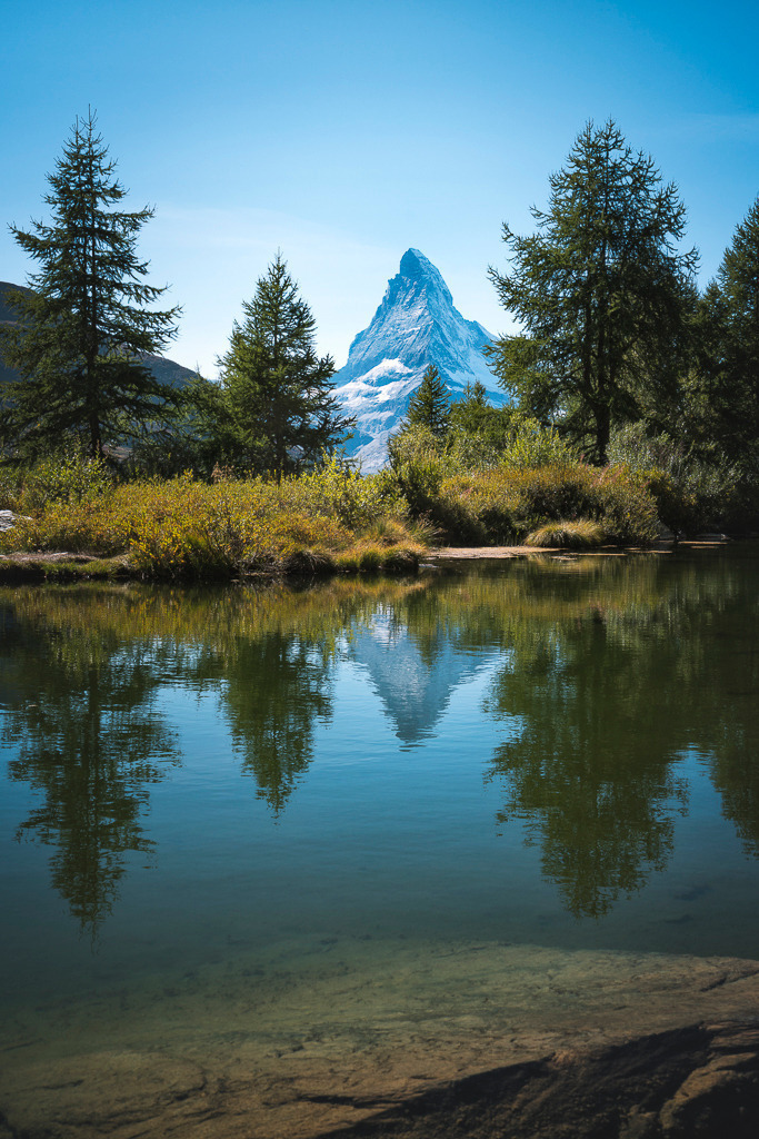 Matterhorn-Spiegelung im Grindjesee | Das Matterhorn spiegelt sich im ruhigen Wasser des Grindjesees bei Zermatt. Die perfekte Symmetrie, das klare Licht und die alpine Vegetation machen dieses Motiv zu einem beliebten Highlight für Natur- und Bergliebhaber. - Realisiert mit Pictrs.com