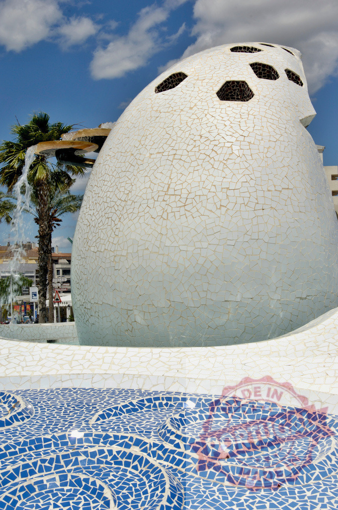 Columbus Egg Monument fountain in Sant Antoni de Portmany. Provincia Castellon - Spain | Columbus Egg Monument fountain displaying blue and white mosaic tiles under a sunny sky - Realized with Pictrs.com