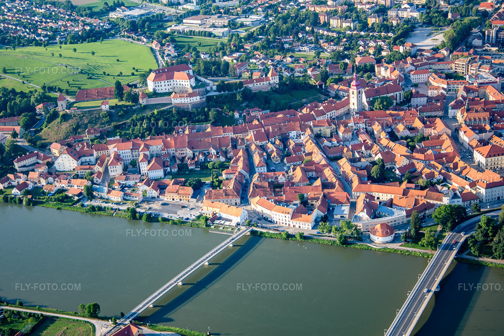 Aerial view: Old town from the south, behind the bridges over the Drava/Dravo in Ptuj in the state Slovenia, Slovenia. – Photo: IMG_137319.jpg taken on 07/08/2023 by Werner Riehm/FLY-FOTO.com – Resolution of the original: 5472 x 3648 px