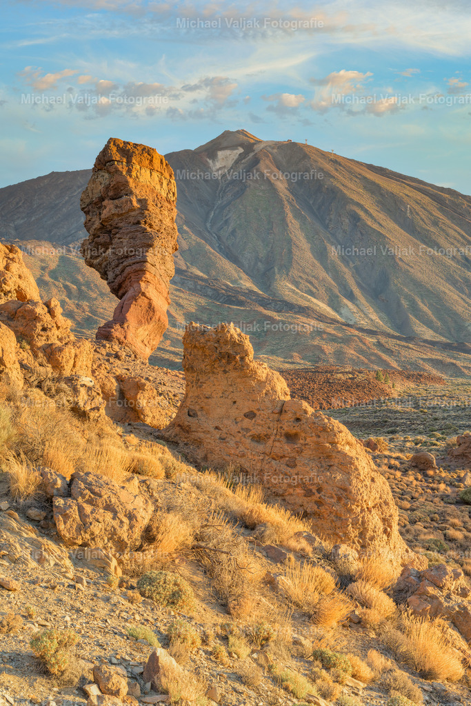Roque Cinchado und Teide im Morgenlicht | Der Roque Cinchado, ein markantes Wahrzeichen Teneriffas, ist Teil der Roques de García, einer beeindruckenden Felsformation im Teide-Nationalpark. Diese Formationen, die durch vulkanische Aktivität und Erosion über Millionen von Jahren entstanden sind, bieten im Morgenlicht einen atemberaubenden Anblick. Der Teide selbst, Spaniens höchster Gipfel, erhebt sich majestätisch im Hintergrund und vervollständigt das spektakuläre Panorama, das manche Besucher früh am Tag suchen, um die warmen Farben des Sonnenaufgangs einzufangen. - Realisiert mit Pictrs.com