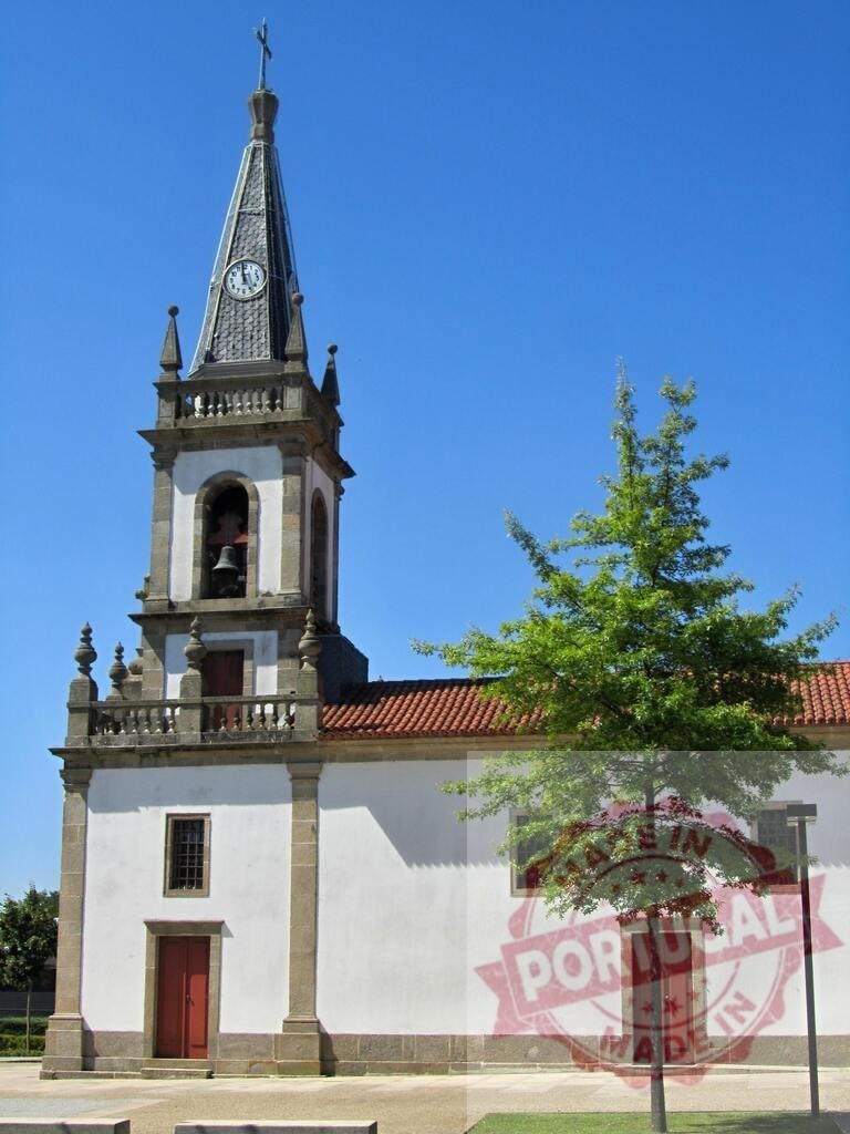 Portuguese church bell tower with clock steeple pointing to blue sky. Norte - Portugal | White church building with a classic bell tower and red roof under clear blue sky - Realized with Pictrs.com