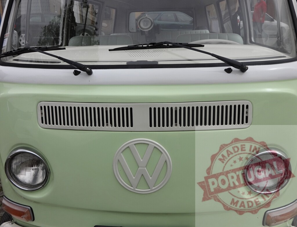 Volkswagen van showing its front, wipers and logo | Close-up of the front of a Volkswagen van, highlighting its distinctive design, pastel green color, wipers and iconic logo - Realized with Pictrs.com
