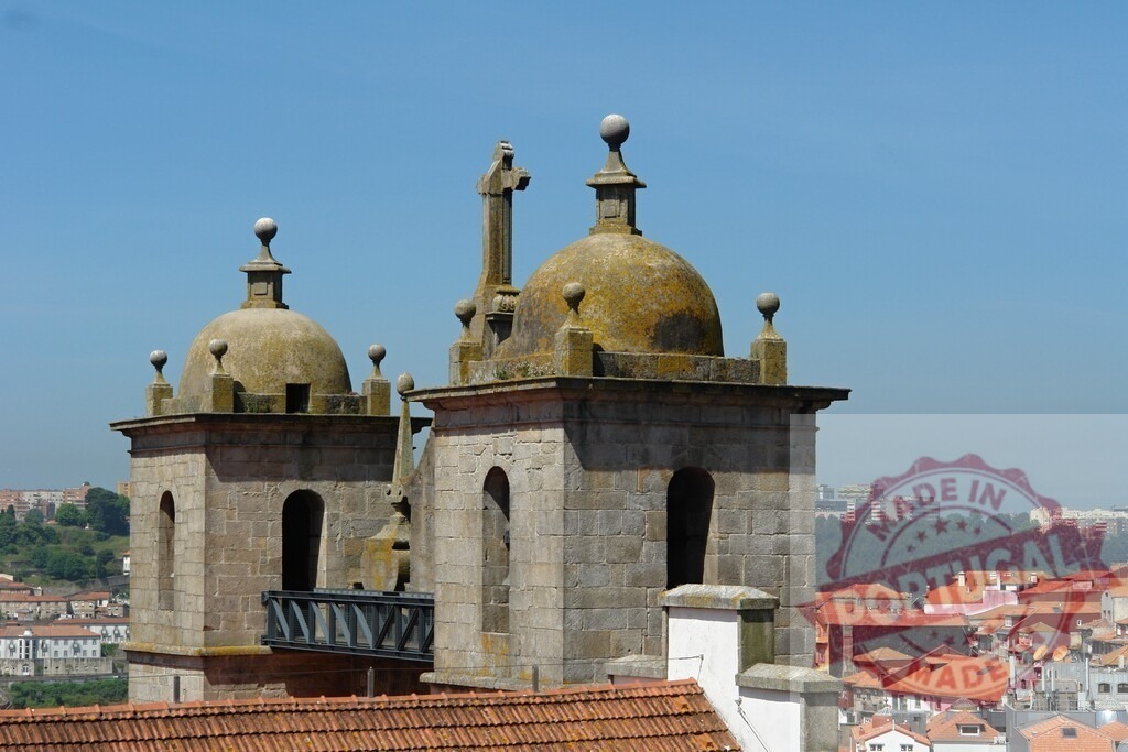 Porto Cathedral towers rising above city roofs. Porto - Portugal | Stone cathedral towers and domes against a clear blue sky, overlooking a city skyline - Realisiert mit Pictrs.com