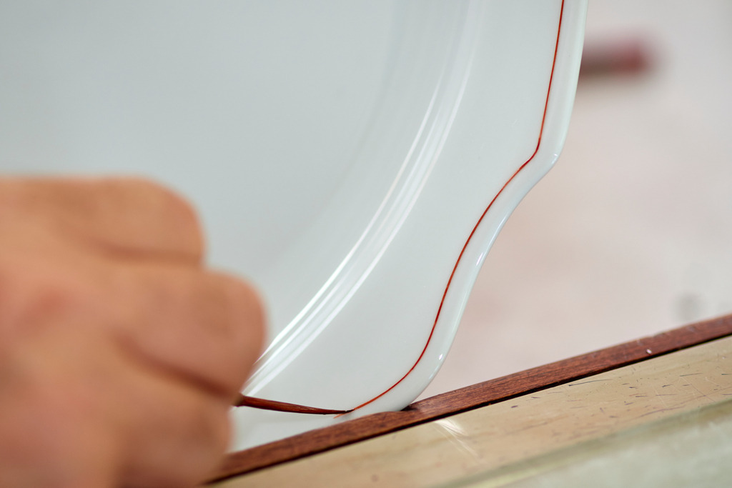 Wiener Porzellanmanufaktur Augarten | Wien, Austria - July 17, 2017: Wiener Porzellanmanufaktur Augarten, Teller wird mit einer Linie verziert. - Realisiert mit Pictrs.com