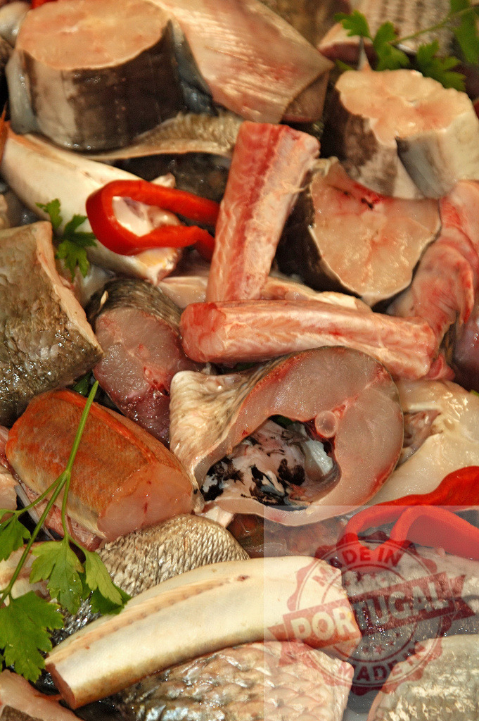 Raw fish pieces selling at market stall with pepper | Raw fish pieces, scales, and red pepper arranged for sale at a fish market - Realized with Pictrs.com