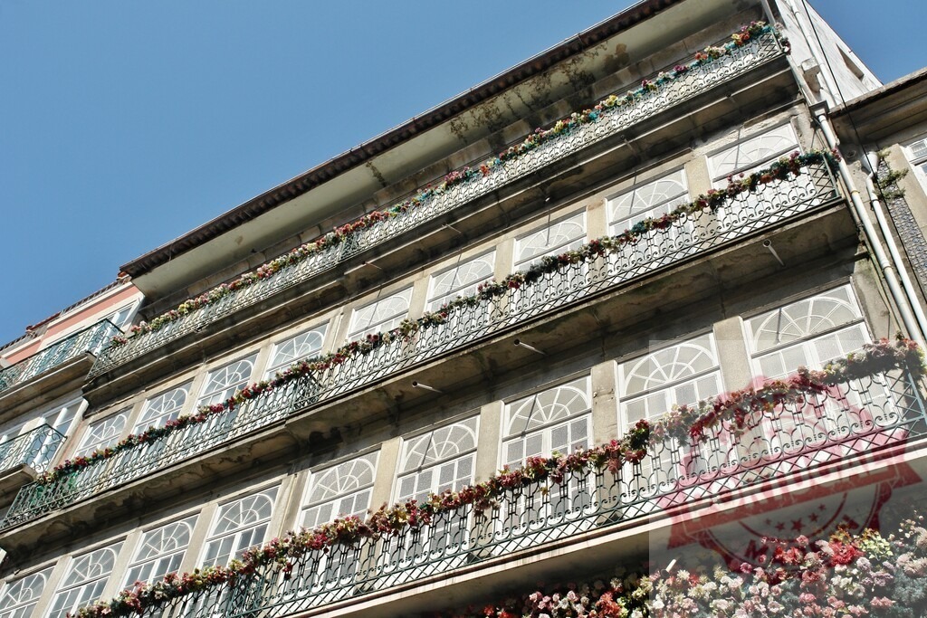 Traditional Porto building balconies decorating with flowers. Porto - Portugal | Traditional architecture building in Porto with balconies full of colorful flowers under a clear sky - Realisiert mit Pictrs.com