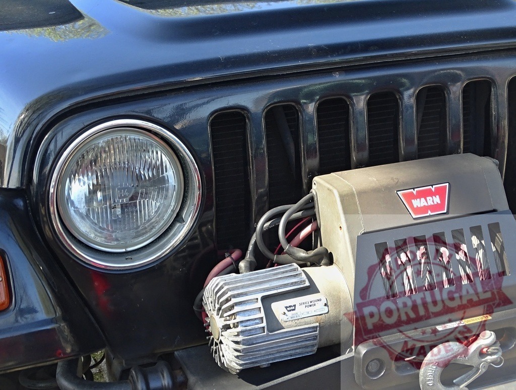 Black Jeep off-road vehicle with Warn winch for recovery | Close-up of a black Jeep off-road vehicle showing the front headlight and Warn winch - Realisiert mit Pictrs.com