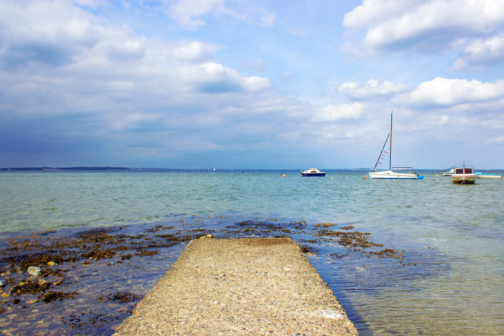 Wandbild: Boote in Habernis – Ruhepunkt an der Flensburger Förde | Dieses Wandbild zeigt einen stillen Moment am Ufer von Habernis – dort, wo die Flensburger Förde ihre maritime Seite offenbart. Ein schmaler Steg führt in das klare, ruhige Wasser, während Segel- und Motorboote sanft auf den Wellen treiben. Die Wolken am Himmel spiegeln sich in der Förde und verleihen dem Bild Tiefe und Bewegung. Ein Motiv, das Sehnsucht nach Meer, Wind und Weite weckt. Erhältlich als Leinwand, Alu-Dibond, Acrylglas, FineArt Papier oder als Akustikbild, bringt dieses Bild maritimes Flair in deine Räume. Ideal für alle, die sich nach Küstenleben, Bootsträumen und norddeutscher Gelassenheit sehnen – ob im Wohnzimmer, Büro oder Ferienhaus. Ein maritimer Moment aus Habernis – klar, ruhig und voller Fernweh. - Realisiert mit Pictrs.com