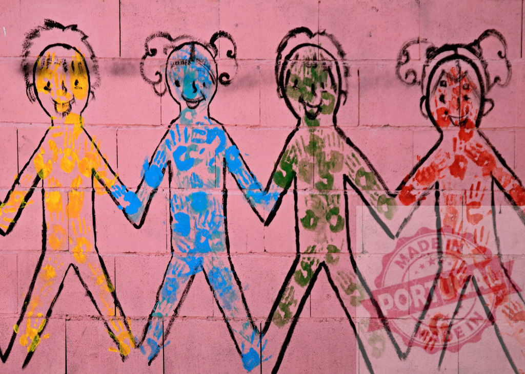 Children holding hands handprints mural symbolizing unity | Colorful children cutouts on a pink wall united through painted handprints - Realized with Pictrs.com