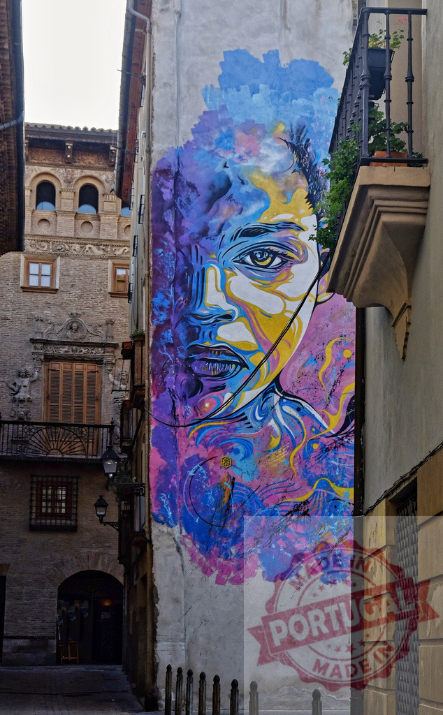 Colorful street art mural depicting woman on building in Valencia Spain | Vibrant urban artwork of a woman's face adorning a narrow alleyway wall - Realisiert mit Pictrs.com