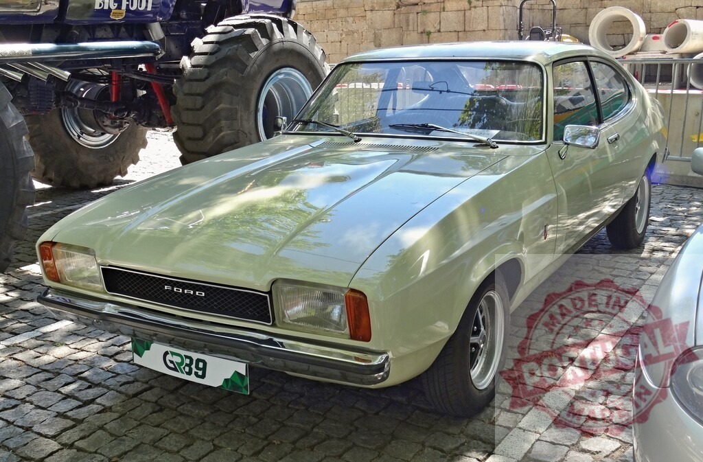 Classic Ford Capri parked near a monster truck | Shiny Ford Capri parked in cobblestone street next to a monster truck - Realized with Pictrs.com