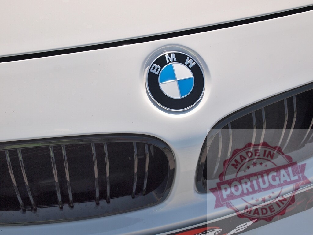 BMW logo on front grille of white automobile | BMW logo prominently featuring on the front grille of a white car - Realized with Pictrs.com