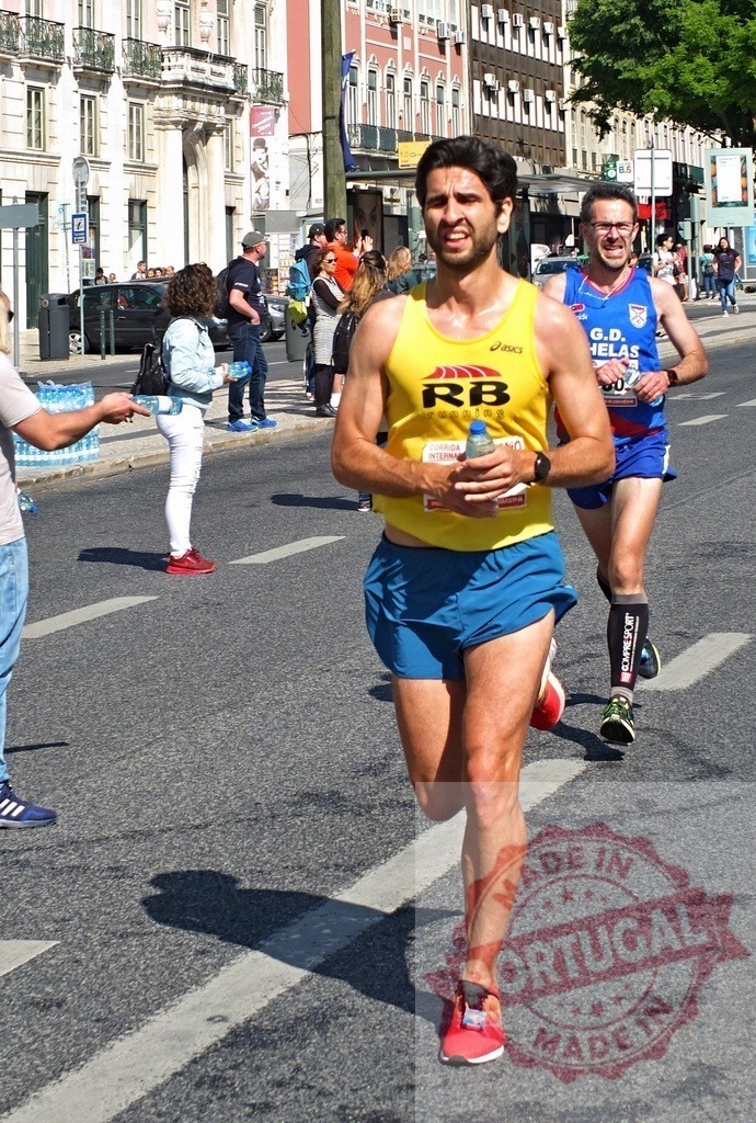 Male runner participating in a marathon in Lisbon | Runner with a water bottle on a city street during a marathon - Realized with Pictrs.com