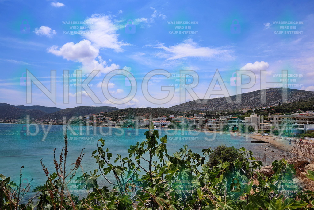 Bucht von Porto Rafti – Attika, Griechenland | Panoramablick auf die geschützte Bucht von Porto Rafti in Attika, Griechenland. Das türkisfarbene Wasser des Saronischen Golfs trifft auf einen sandigen Strand, gesäumt von weißen Ferienhäusern und Hotels, die sich an die bewaldeten Hügel schmiegen. Im Vordergrund rahmen mediterrane Pflanzen die idyllische Szene ein. Ein beliebtes Reiseziel nahe Athen. Das Bild kann als Datei oder Fotoprodukt gekauft werden, z.B. für Reiseberichte, Tourismus-Marketing und Wanddekoration mit griechischem Flair. Bestellen Sie gleich Ihr Wunschprodukt