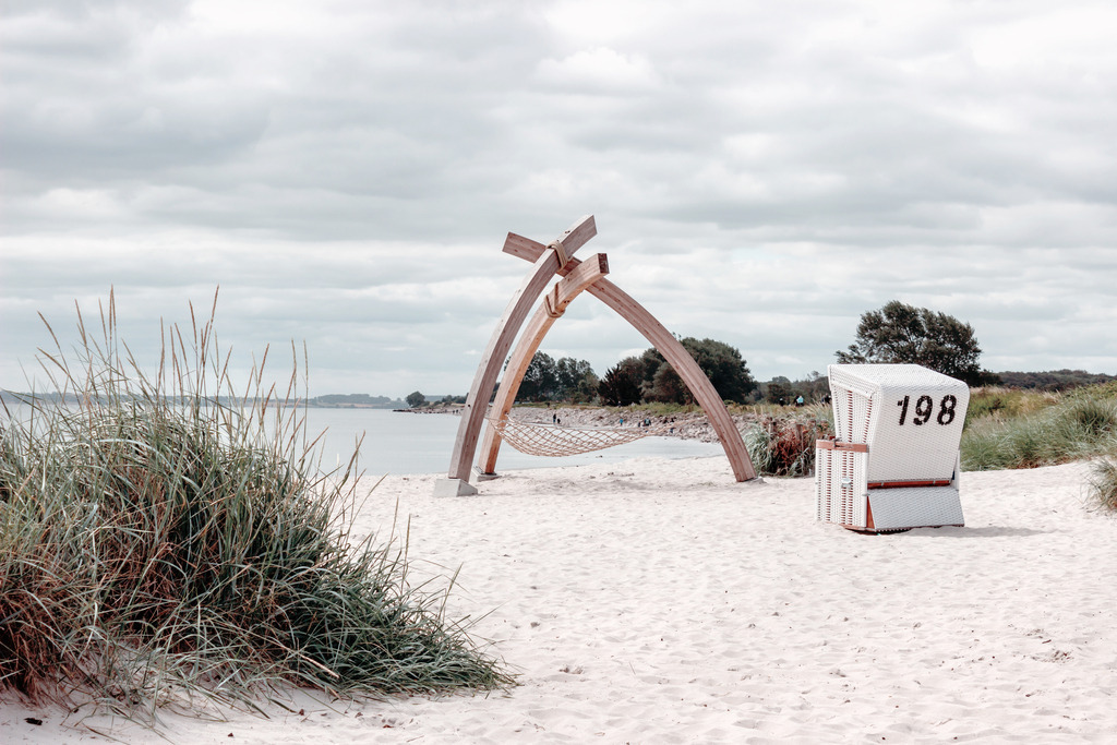 Wandbild: Strandkorb am Sandstrand | Dieses Wandbild im Querformat zeigt einen Strandkorb in weiß am Sandstrand in dezenten Farben. Auf der linken Seite befindet sich Strandhafer. Holen Sie sich mit diesem dekorativen Wandbild den Strandurlaub für das ganze Jahr nach Hause oder an den Arbeitsplatz. Es ist auf Leinwand, auf Alu-Dibond, Acrylglas oder als Holzdruck erhältlich. Die Wandbilder werden individuell für Sie in vielen Abmessungen produziert. Daher passen die Ostseekult Wandbilder immer perfekt an Ihre Wände. - Realisiert mit Pictrs.com