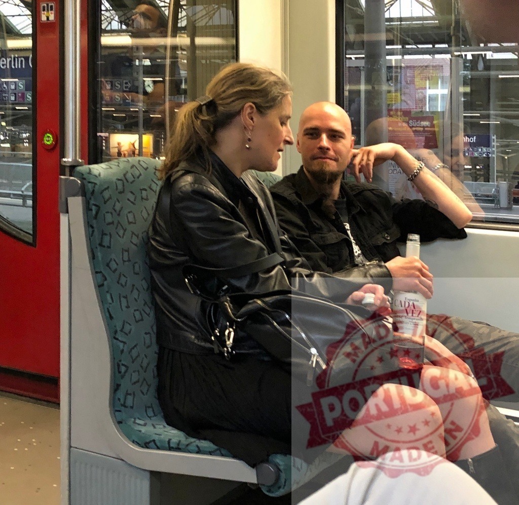 Adult couple drinking alcohol on a public train | Man and woman sharing a bottle of red wine while sitting on a public transport train - Realized with Pictrs.com