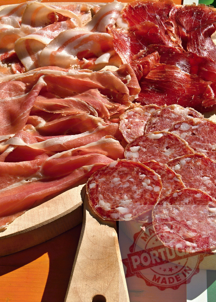 Assorted deli meats charcuterie board serving appetizer | Cured meats platter with various salami and ham slices on a wooden board - Realized with Pictrs.com
