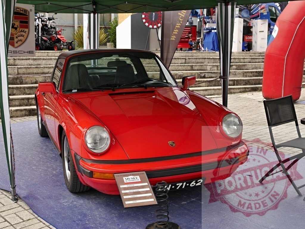 Red Porsche 911 Targa classic car at outdoor exhibit | Vibrant red Porsche 911 Targa parked under a tent at an outdoor car show - Realisiert mit Pictrs.com