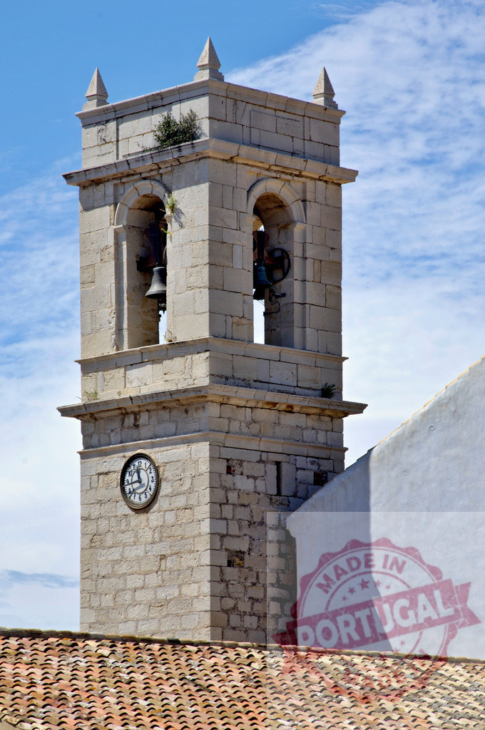 Ancient church tower standing with bells and clock. Provincia de Castellon | Stone bell tower with a clock against a bright blue sky - Realisiert mit Pictrs.com