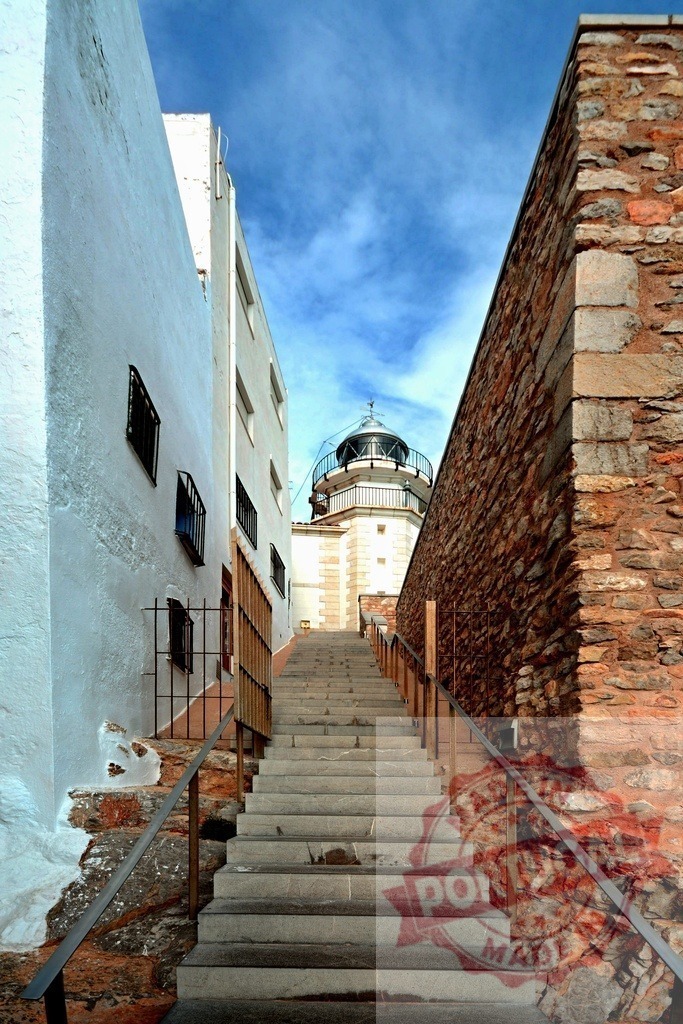 Stairway leading to the Peniscola lighthouse in Spain | Stone stairway leading to the top of a lighthouse, between a white wall and a stone wall, with a blue sky - Realized with Pictrs.com