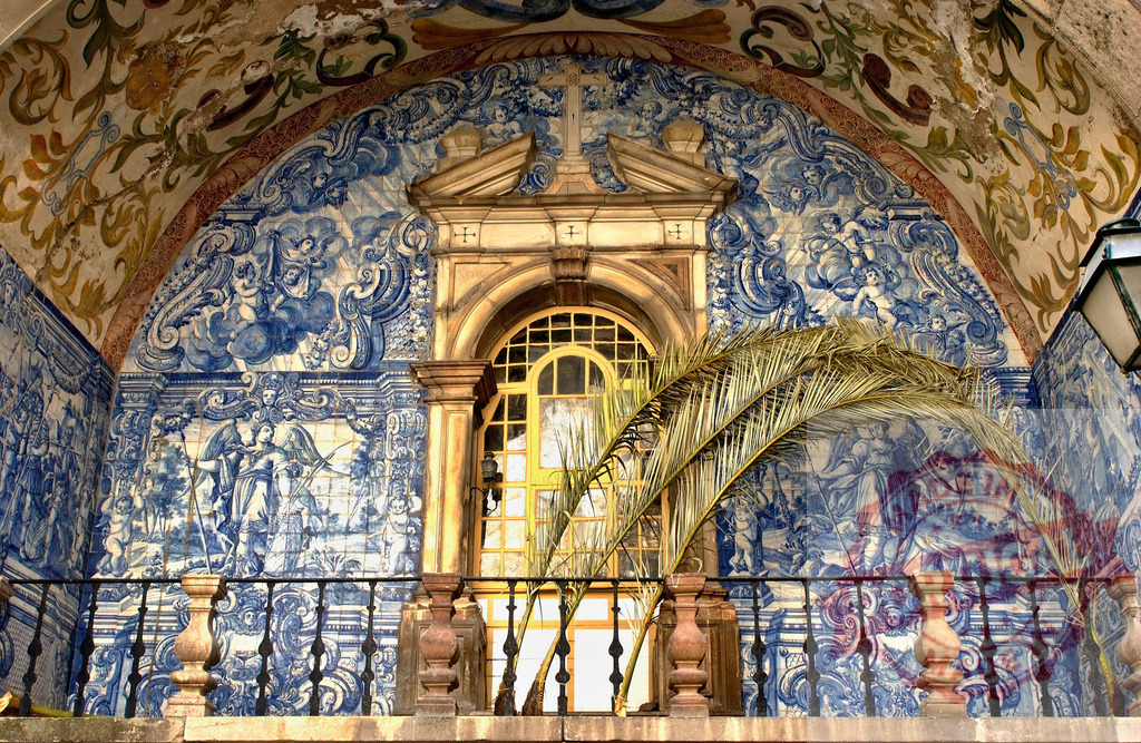 Ornate Portuguese azulejo tiles decorating a church balcony | Elaborate azulejo murals and a painted archway adorning a historic church facade - Realized with Pictrs.com