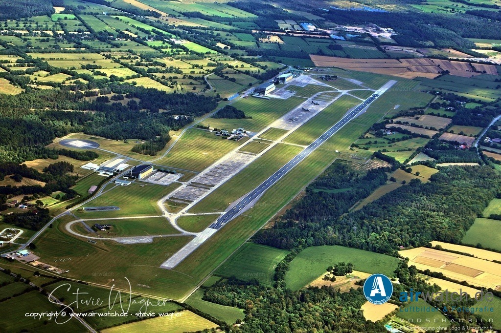 Luftbild Fliegerhorst Hohn - Im Zuge der Neuausrichtung der Bundeswehr wurde 2015 beschlossen, das LTG 63 bis Ende 2021 aufzulösen | Im Zuge der Neuausrichtung der Bundeswehr wurde 2015 beschlossen, das LTG 63 bis Ende 2021 aufzulösen, da der Airbus A400M nicht rechtzeitig einsatzbereit war. Aufgrund der weiterhin notwendigen Einsatzfähigkeit der Transall C-160 wurde der Betrieb bis 2021 verlängert, und der Standort sollte erst Mitte 2022 geschlossen werden. Im Dezember 2019 entschied die Bundeswehr jedoch, den Standort mit seinen rund 650 Soldaten und mehr als 80 zivilen Mitarbeitern dauerhaft weiterzunutzen.