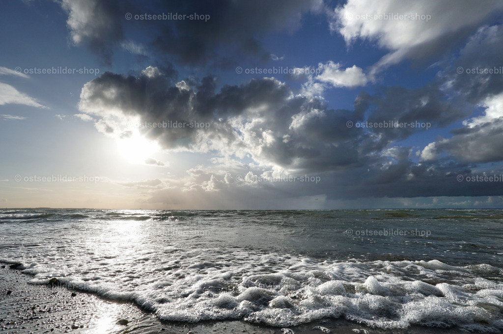 Zwischen Meer und Wolken | In diesem Bild fällt der Blick auf die grelle Sonne über der Ostsee am späten Nachmittag. Kräftige Cumuluswolken korrespondieren formal mit den auslaufenden Schaumkronen im Vordergrund.