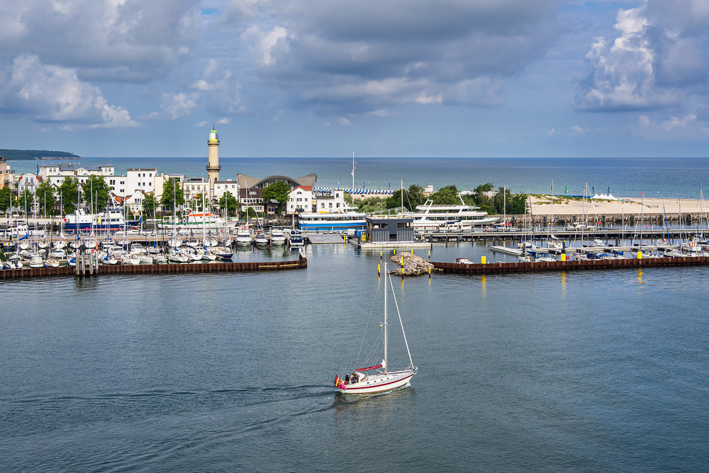 Leuchtturm und Segelboot an der Ostseeküste in Warnemünde am Abend | Leuchtturm und Segelboot an der Ostseeküste in Warnemünde am Abend.