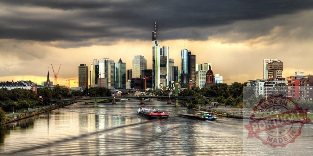 Frankfurt skyline cityscape on Main River with barges under stormy sunset | Frankfurt skyline with modern skyscrapers reflecting light, Main River water flowing, and barges moving - Realized with Pictrs.com