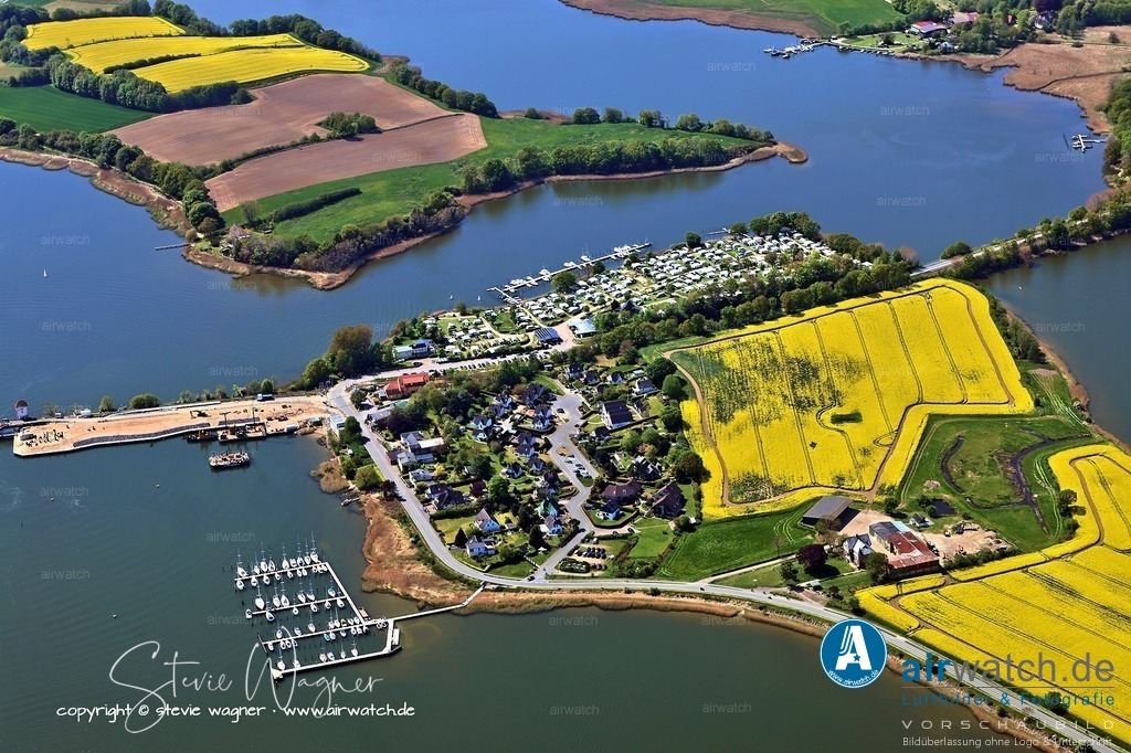 Luftbild Ostseefjord Schlei, Boren-Lindaunis Schleibrücke, Campingplatz Lindaunis, Sportboothafen Lindaunis | Sportboothafen Lindaunis - Anreise und Anfahrt >> Per Boot: Der Hafen liegt nordöstlich der Lindaunis-Klappbrücke direkt am Schleifahrwasser. Er ist unkompliziert anzusteuren, da die Anleger bis in tiefe Gewässer (bis zu 3,5 m) reichen. Steuern Sie auf die Koordinaten 54.586150, 9.822664 zu. >> Per Bahn: Nutzen Sie die stündliche Verbindung der Linie Flensburg–Kiel. Vom Bahnhof Lindaunis aus sind es etwa 7 Gehminuten zum Hafen – ideal für ankommende Crews oder Besucher. >> Per Auto: Fahren Sie über die B 203 in Richtung Lindaunis. Der Hafen ist ausgeschildert. Parkplätze stehen am Hafen zur Verfügung. >> Die Adresse fürs Navi: Schleistraße 11, 24392 Lindaunis. >> Per Fahrrad oder zu Fuß: Der Hafen ist Teil des Radwegenetzes an der Schlei. Von Lindau oder Boren aus führen gut ausgebaute Wege direkt zum Hafen.