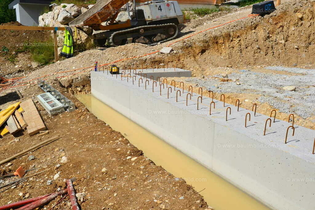 Betonierte Frostschürze | Streifenfundament aus Beton als Frostschürze mit Steckeisen, Wasser in Fundamentgraben