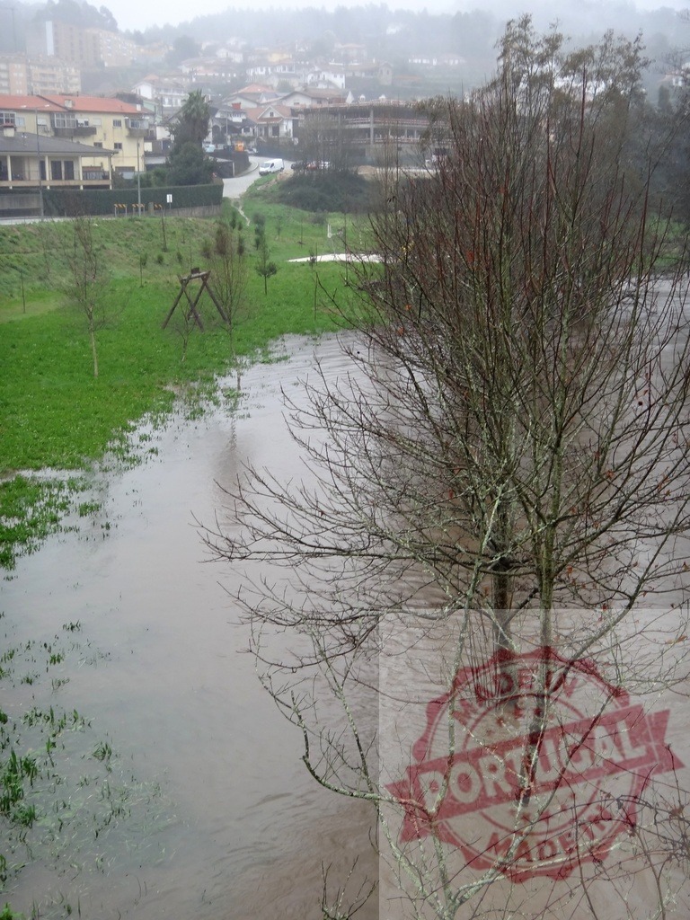 River overflowing bank flooding surrounding village area. Portugal floods 02.26 - Paco de Sousa, Penafiel | River overflowing its banks after heavy rain, submerging parts of the natural park alongside - Realisiert mit Pictrs.com