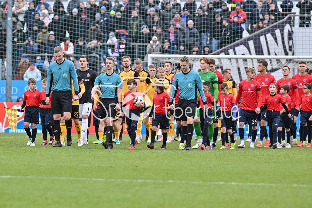 SpVgg Unterhaching - Dynamo Dresden | Die beiden Mannschaften laufen zusammen ein / Schiedsrichter Jarno WIENEFELD in Aktion / Linienrichter Florian POETTER in Aktion / Linienrichter Marvin TENNES in Aktion / 3. Liga: SpVgg Unterhaching - Dynamo Dresden, Uhlsportpark am 21.12.2024