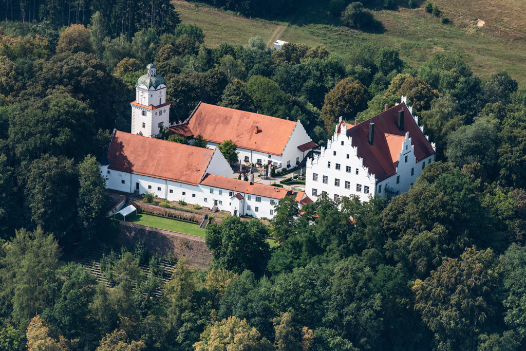 dr__0016365.jpg | NEUBURG AN DER KAMMEL 03.08.2018 Schloss Neuburg an der Kammel in Neuburg im Bundesland Bayern. Zusammen mit der Pfarrkirche St. Mariae Himmelfahrt bestimmt der Gebäudekomplex aus dem dreigeschossigen Hauptbau mit Satteldach und zinnenbesetztem Giebel, zweischiffiger Kapelle, Turm und Wirtschaftsgebäuden, das Ortsbild. Das Schloss wurde 1552 erbaut und heute als Gastronomiebetrieb genutzt. // Castle Neuburg an der Kammel in Neuburg in the state of Bavaria. The historic building complex with the parochial church St. Mariae Himmelfahrt beneath it and the three storey main building, the gabled roof with battlements, the two ship chapel and the tower and outbuildings,  is a landmark of the village. The castle was built in 1552 and is used as a restaurant today. Foto: Daniel Reiter