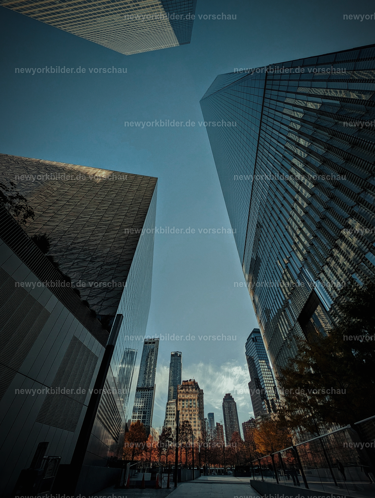 Wolkenkratzer in Downtown Manhattan – Blick nach oben zwischen imposanten Gebäuden | Mitten in Downtown Manhattan: Wolkenkratzer ragen wie Giganten in den Himmel, während wir Menschen winzig wirken. Ein Bild, das die monumentale Architektur und die überwältigende Energie von New York City perfekt einfängt.