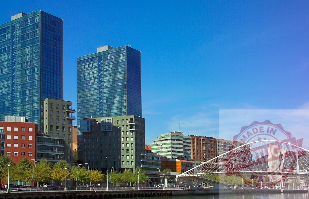 Bilbao skyline featuring modern buildings and Zubizuri Bridge. Spain - Bilbao | Bilbao cityscape showcasing contemporary architecture along the Nervion River under a clear sky - Realized with Pictrs.com