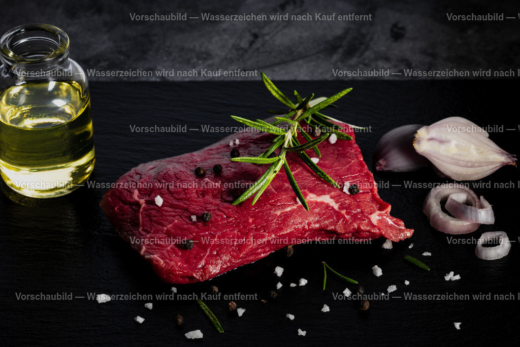 rohes Rinder Hüftsteak auf schwarzer Schieferplatte angerichtet | rohes Rinder Hüftsteak auf schwarzer Schieferplatte angerichtet. Dekoriert mt einen Zweig Rosmarien, Pfefferkörnern, Schalotten, Öl und groben Salz - Realisiert mit Pictrs.com
