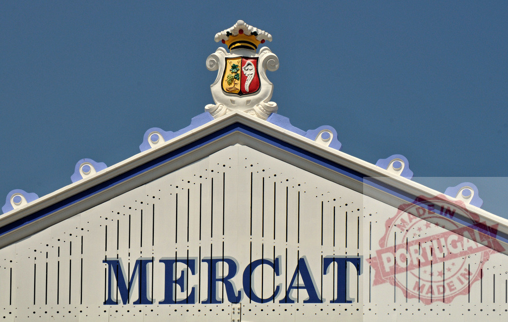 Mercat sign and crest on market building facade | Mercat sign and heraldic crest on a traditional market building under blue sky - Realisiert mit Pictrs.com