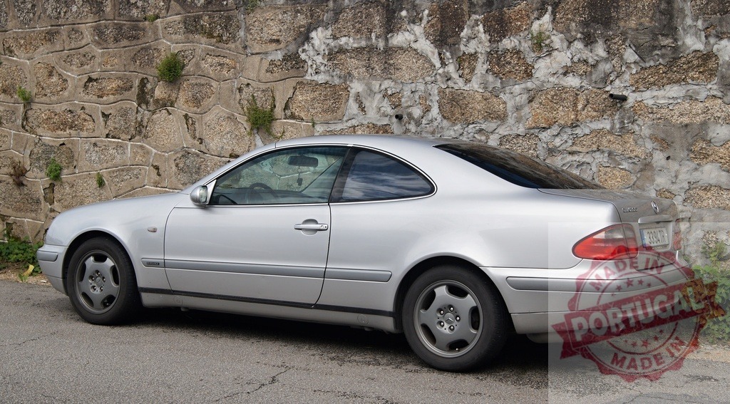 Mercedes-Benz CLK silver coupe parked by stone wall | Silver Mercedes-Benz CLK coupe parked next to an old stone wall during daytime - Realisiert mit Pictrs.com