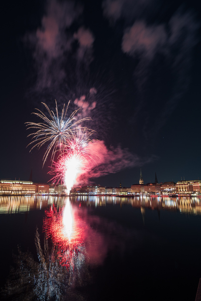 Feuerwerk und Spiegelung in Hamburg | Eine Feuerwerkskomposition über der Hamburger Alster mit leuchtenden Fontänen, dramatischen Rauchwolken und einer markanten Spiegelung im Wasser. - Realisiert mit Pictrs.com